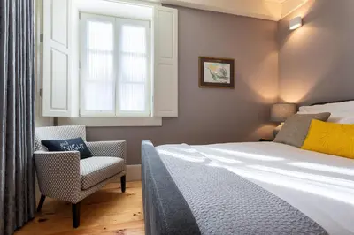 a bedroom with a bed and a chair and a window at Lemon Mezzanine - Santa Catarina in Porto