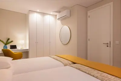 a white bedroom with a bed and a mirror at Palmeiras Apartment, by Bolhão Residences in Porto