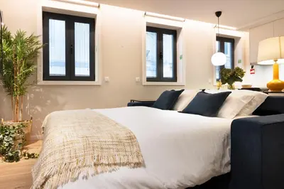 a bedroom with a large white bed and windows at Palmeiras Apartment, by Bolhão Residences in Porto