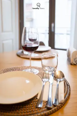 a table with a plate and a glass of wine at Locally Yours Flores Apartments in Porto
