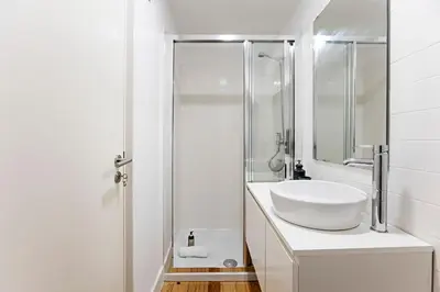 a white bathroom with a sink and a shower at D. João IV Apartments by LovelyStay in Porto