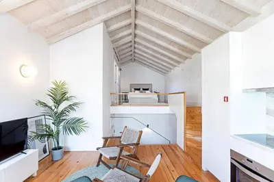 a living room with white walls and a wooden ceiling at D. João IV Apartments by LovelyStay in Porto