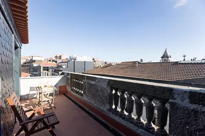a balcony with two chairs and a view of a city at Aliados Premium 1BR w/ Terrace by LovelyStay in Porto