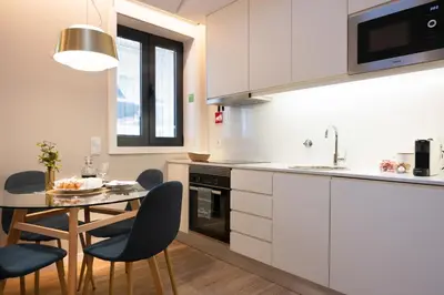 a kitchen with white cabinets and a table and chairs at Savannah Apartment, by Bolhão Residences in Porto