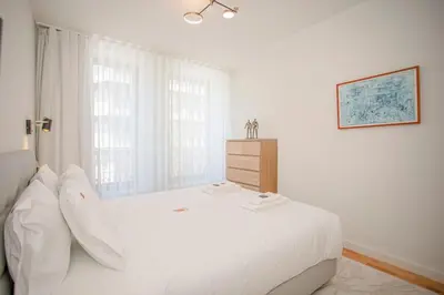 a white bedroom with a large bed and a window at Liiiving in Porto - Design Bright House in Porto