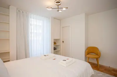 a white bedroom with a bed and a chair at Liiiving in Porto - Design Bright House in Porto