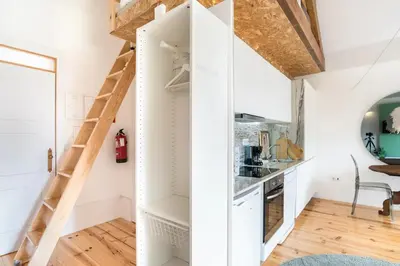a small kitchen with white cabinets and a ladder at Studio Duplex w/ AC In Praça República by LovelyStay in Porto