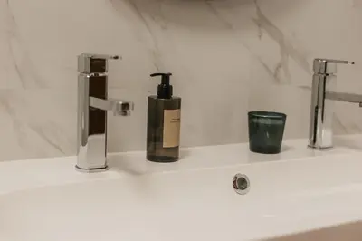 a bathroom sink with a bottle of soap on it at Apartamento Santos Pousada in Porto