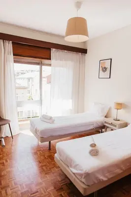 a bedroom with two beds and a large window at Apartamento Santos Pousada in Porto
