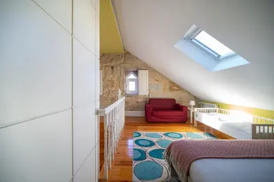 a attic bedroom with a bed and a red chair at Near Boavista - Free Parking in Porto