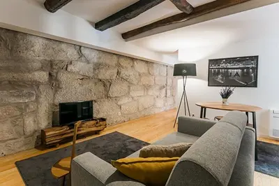 a living room with a couch and a stone wall at Stay In Apartments in Porto