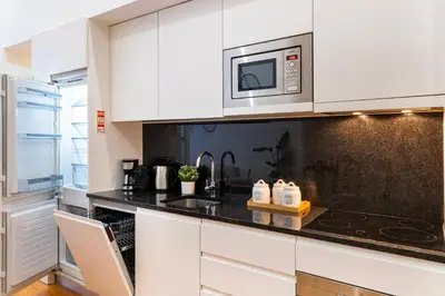a kitchen with white cabinets and a microwave at Majestic Cafe - Porto City Center Modern Apartment in Porto