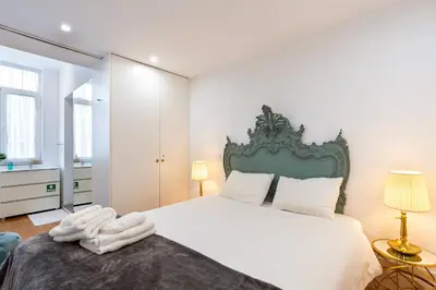 a bedroom with a white bed with a green headboard at Majestic Cafe - Porto City Center Modern Apartment in Porto