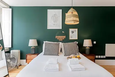 a bedroom with a large white bed with a green wall at Lóios 66 by LovelyStay in Porto