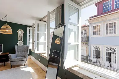 a room with large windows and a chair in front at Lóios 66 by LovelyStay in Porto
