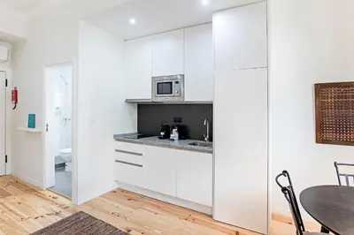 a kitchen with white cabinets and a table and a microwave at 150 Rivoli Apartments by LovelyStay in Porto