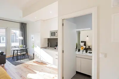 a kitchen and living room with white cabinets and a mirror at 150 Rivoli Apartments by LovelyStay in Porto