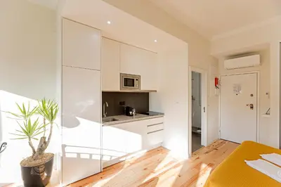 a kitchen with white cabinets and a table with a plant at 150 Rivoli Apartments by LovelyStay in Porto