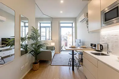 a kitchen and living room with a table and a couch at 31 Janeiro 157 - Delightful 1BR Flat w/ AC & Balcony by LovelyStay in Porto