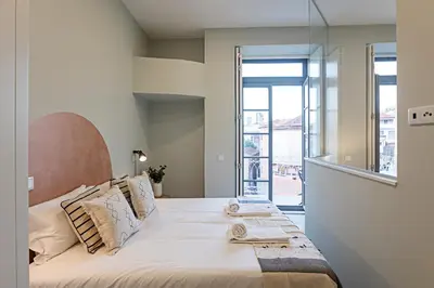 a bedroom with a bed with a large window at 31 Janeiro 157 - Delightful 1BR Flat w/ AC & Balcony by LovelyStay in Porto
