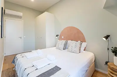 a bedroom with a large white bed with two towels on it at 31 Janeiro 157 - Delightful 1BR Flat w/ AC & Balcony by LovelyStay in Porto