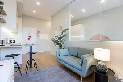 a living room with a couch and a kitchen at 31 Janeiro 157 - Delightful 1BR Flat w/ AC & Balcony by LovelyStay in Porto
