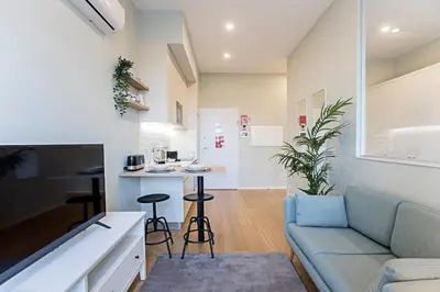 a living room with a couch and a kitchen at 31 Janeiro 157 - Delightful 1BR Flat w/ AC & Balcony by LovelyStay in Porto