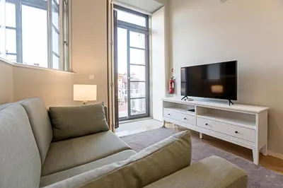 a living room with a couch and a flat screen tv at 31 Janeiro 157 - Delightful 1BR Flat w/ AC & Balcony by LovelyStay in Porto