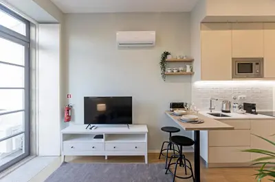 a kitchen with a tv and a counter with stools at 31 Janeiro 157 - Delightful 1BR Flat w/ AC & Balcony by LovelyStay in Porto