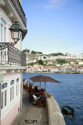 a group of people sitting under an umbrella on a pier at 1872 River House by Olivia in Porto