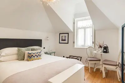 a white bedroom with a large bed and a table at 1872 River House by Olivia in Porto