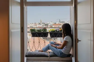 a woman sitting on a window sill looking outside at Skyline Cosy House, Downtown Porto near metro in Porto