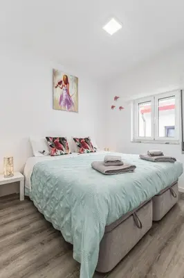 a white bedroom with a large bed with green sheets at Casa do Barqueiro - Porto in Porto