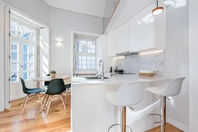 a kitchen with white walls and a table and chairs at Cedofeita Balcony with Free Parking in Porto