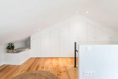 a living room with white cabinets and a wooden floor at Cedofeita Balcony with Free Parking in Porto