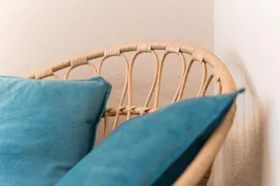 a wicker chair with blue pillows on it at GuestReady - OPortoGrow Central Batalha 2 in Porto