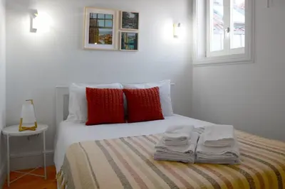 a white bed with red pillows and towels on it at A Window to Porto - Fabulous apartment by Douro River in Porto