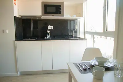 a kitchen with white cabinets and a microwave and a table at room Select Porto Suites in Porto