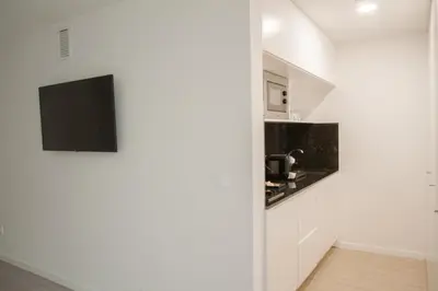 a white kitchen with a tv on a wall at room Select Porto Suites in Porto