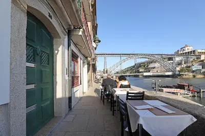 a building with tables and chairs with a view of a bridge at FLH Porto Ribeira with River View in Porto