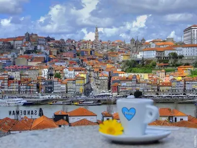 a cup of coffee sitting on a table next to a city at FLH Porto Ribeira with River View in Porto