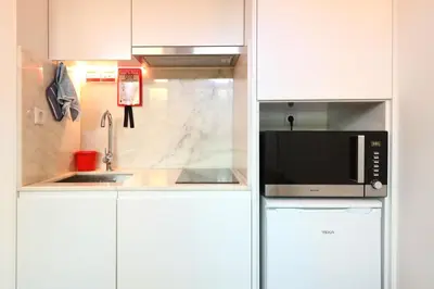 a white kitchen with a microwave and a sink at FLH Porto Santa Catarina Cosy Flat in Porto