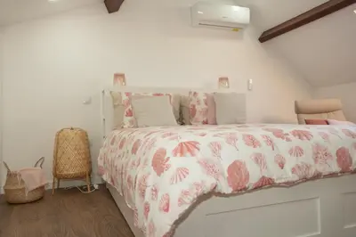 a bedroom with a bed with a pink and white comforter at Fervença Great Stay Apartment in Vila Nova de Gaia