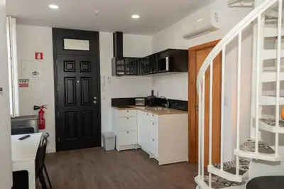 a small kitchen with white cabinets and a black door at Fervença Great Stay Apartment in Vila Nova de Gaia