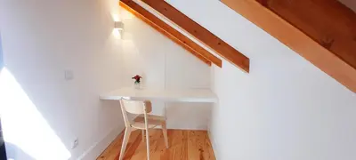 a small white table in the corner of a room with a chair at A Window to Porto St. Helena in Porto