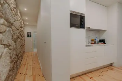 a kitchen with white cabinets and a stone wall at Swimming Pool Luxury House, with AC Downtown Porto in Porto