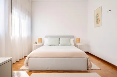 a white bedroom with a large bed with white walls at ! Bright 2BR Hammock Flat ! Praça da República in Porto