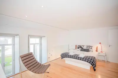 a white bedroom with a bed and a chair at Liiiving in Porto - Garden Light Mezzanine in Porto