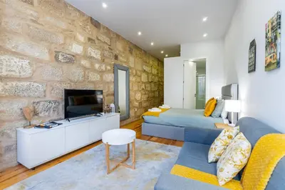 a living room with a blue couch and a stone wall at A Window to Porto - Premium apartment by the River in Porto