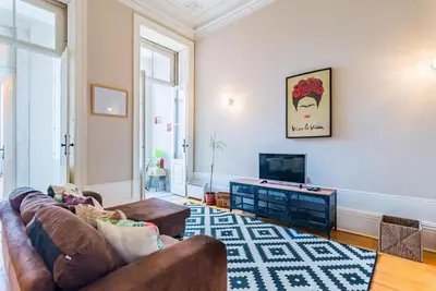 a living room with a couch and a television at Classy Flat at Marques Square with Garden in Porto
